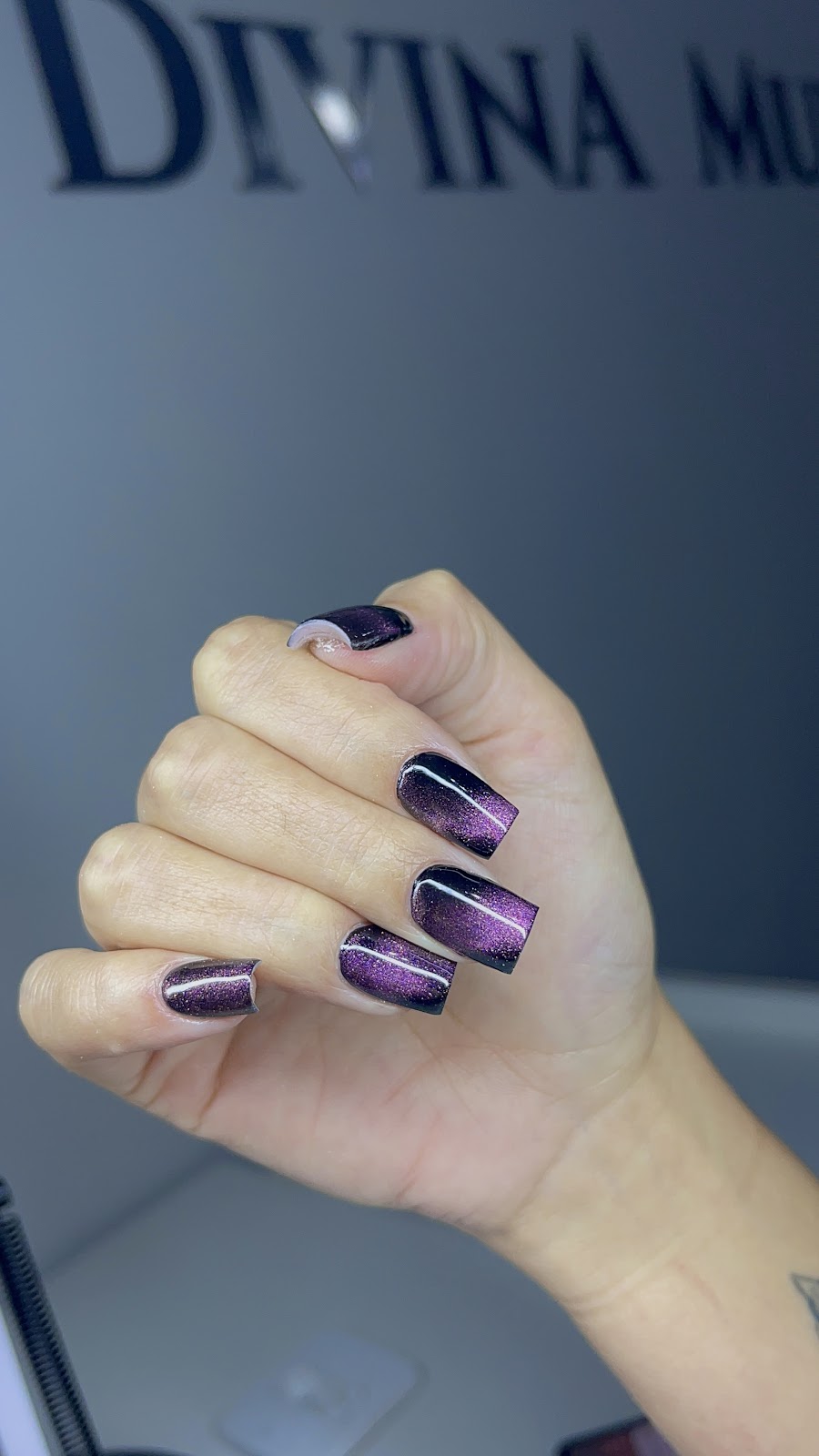 Unhas em roxo com a fachada do Divina Mulher Studio ao fundo